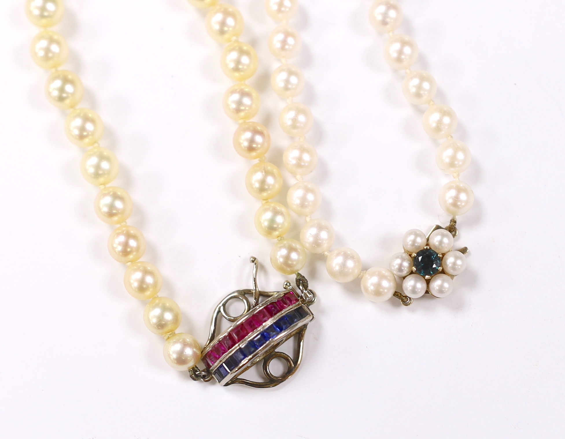 Two single strand cultured pearl necklaces, including one with channel set ruby and sapphire set white metal clasp, 50cm.